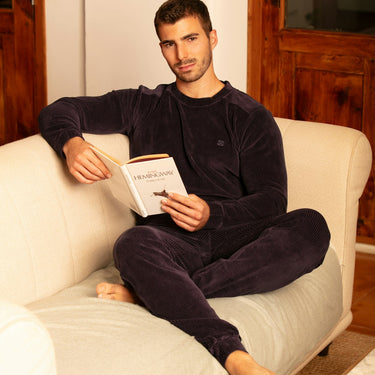 Man sitting on a couch reading a book in a cozy room.